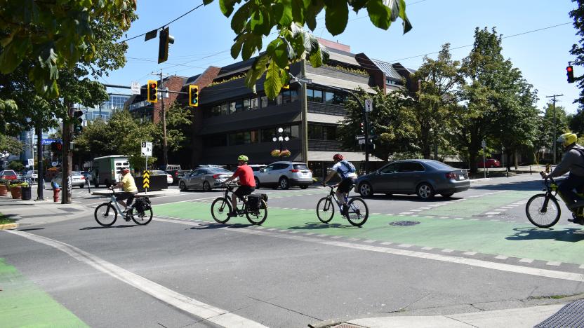 Cars and cyclists moving through a downtown intersection.