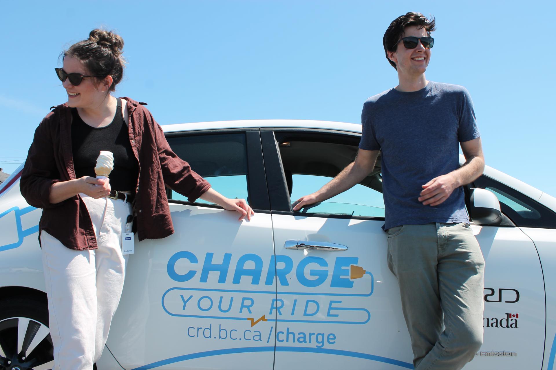 Outreach staff leaning on CRD Charge Your Ride branded electric vehicle